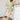 Toddler standing safely on a wooden Montessori learning tower at the kitchen counter, washing hands under running water and engaging in everyday kitchen activities.